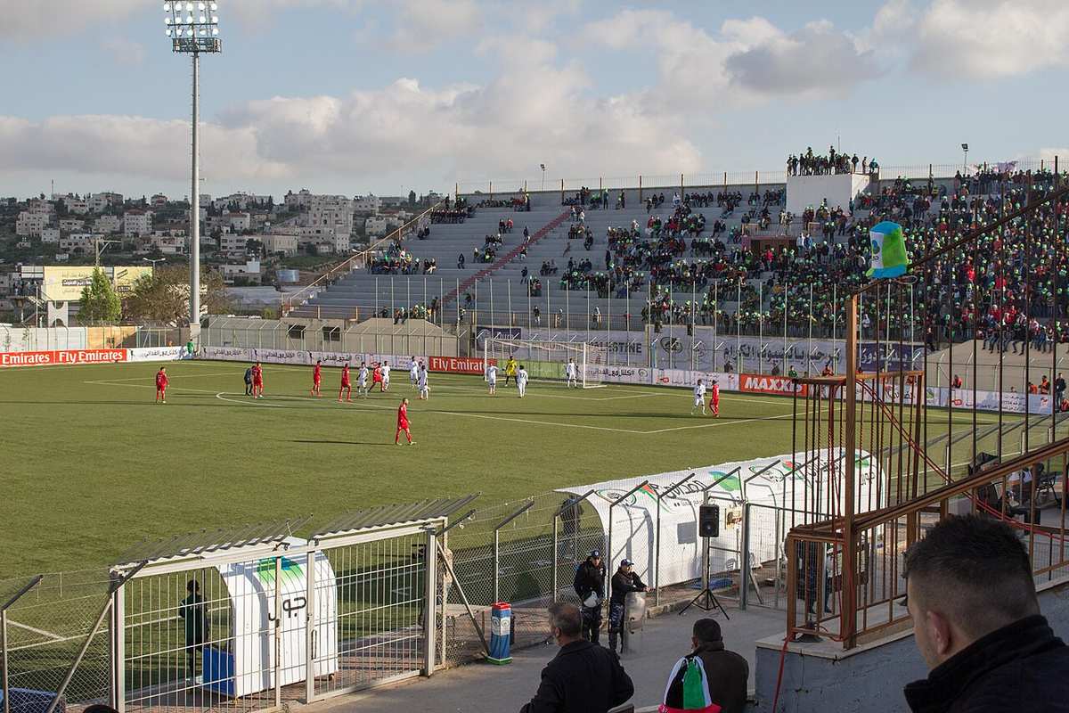 A crowd watching a football match inside a stadium