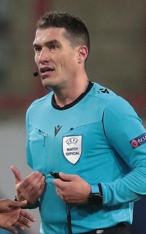 A football referee standing on the pitch during a match
