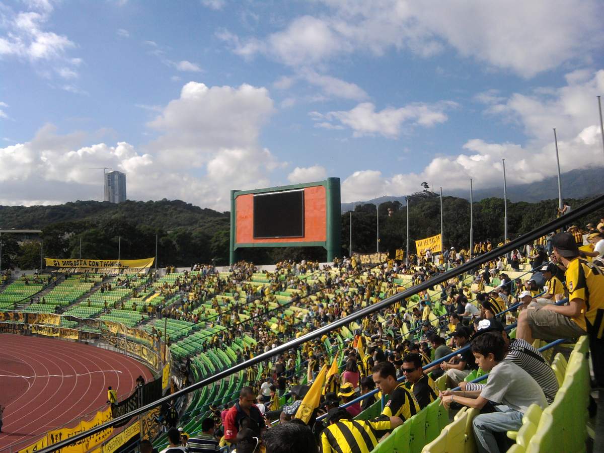 Aficionados del Deportivo Táchira en la tribuna, con banderas y camisetas del club aurinegro