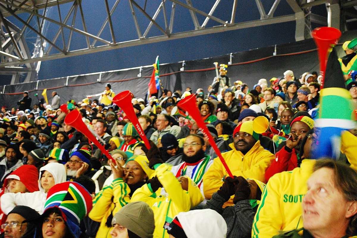 Aficionados sudafricanos celebrando en un estadio durante un partido de fútbol