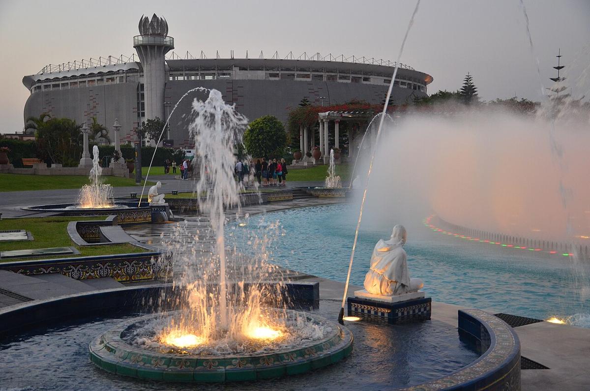 Exterior del Estadio Nacional de Lima con su torre característica y las fuentes de la plaza en primer plano