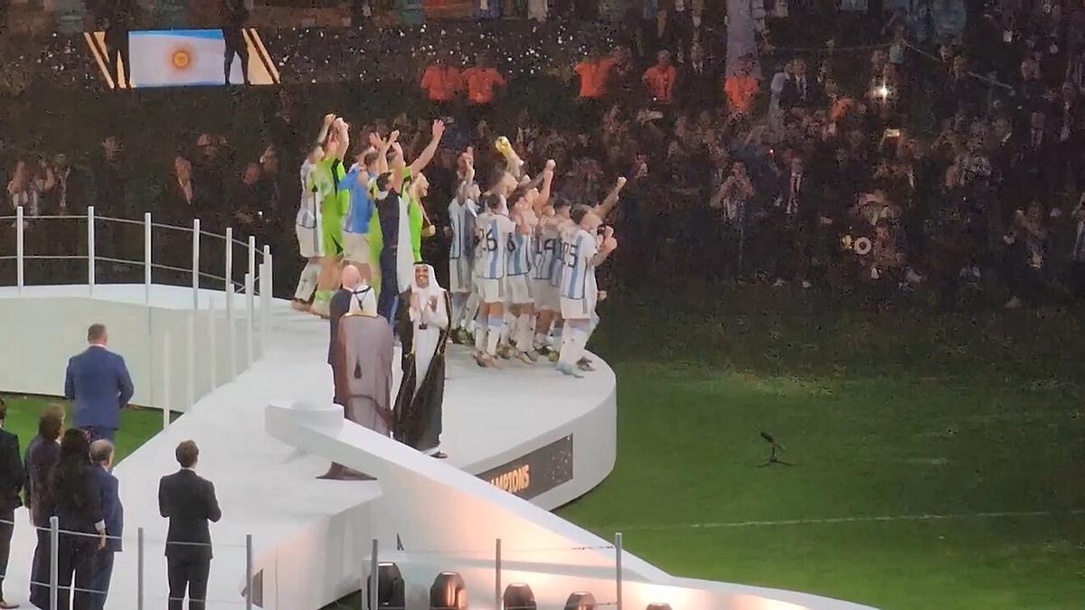 Jugadores de Argentina celebrando juntos sobre el podio con el trofeo en el estadio Lusail